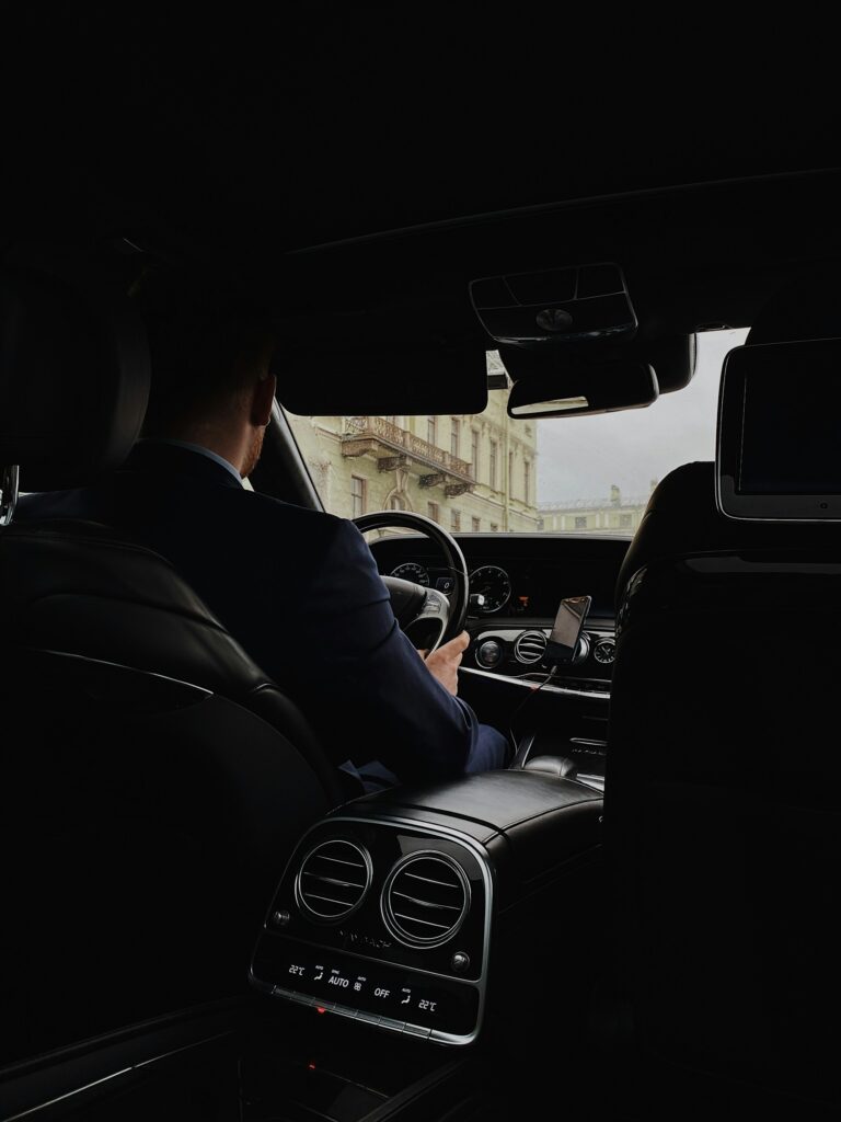 Chauffeur am Steuer einer Limousine, gesehen aus dem Fond